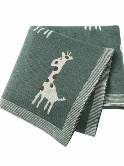 On voit une couverture pliée en quatre sur fond blanc. elle est gris-vert et ornée de petites girafes grises et marron.