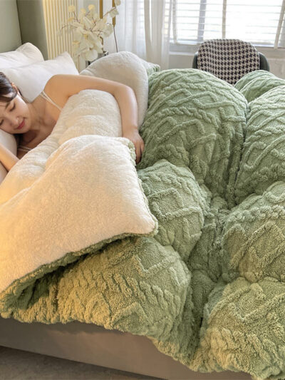 Femme dormant dans un lit avec une couverture épaisse verte.