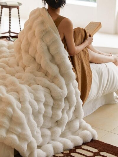 Femme lisant un livre de dos et couverte d'une couverture blanche.