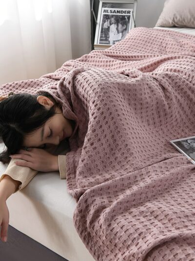 Femme allongé sur un lit et couverte d'une couverture rose.