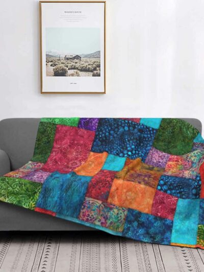 Photo d'une couverture imprimé patchwork multioclore sur un canapé.