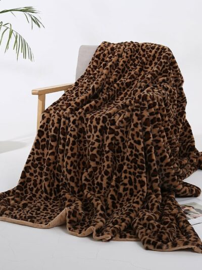 Photo d'une couverture en fausse fourrure léopard marron posée sur une chaise dans un décor minimaliste avec une petite plante dans le fond.