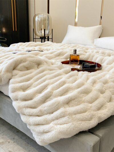 Photo d'une couverture imitation fourrure blanche avec effet de texture posée sur un lit.