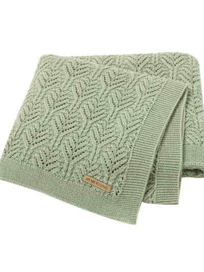 On voit une superbe couverture en tricot dont les mailles sont en forme de feuilles. Elle est verte et vraiment jolie.