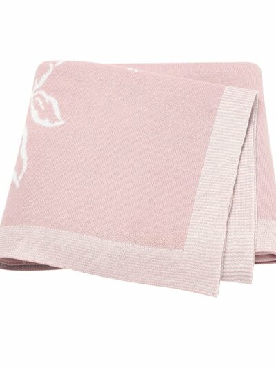 On voit une couverture en mailles fines rose pliée en quatre sur fond blanc. Le bord est rose clair. Il y a un motif floral sur le côté.