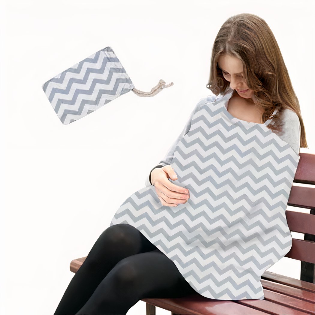 Femme assise sur un banc avec une couverture grise d'allaitement et une petite pochette à côté