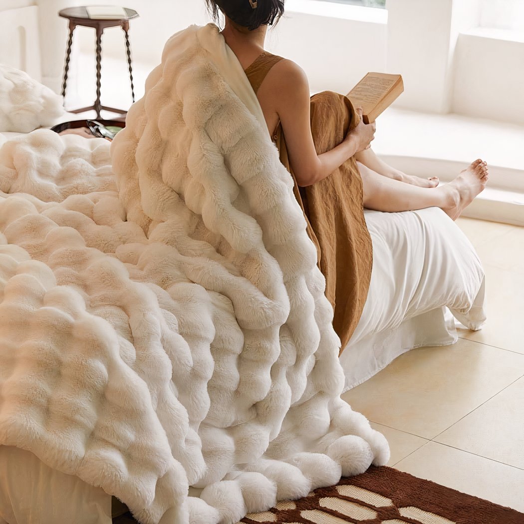Femme lisant un livre de dos et couverte d'une couverture blanche.