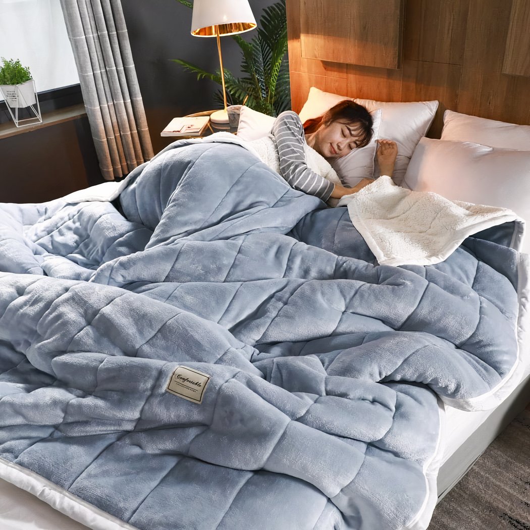 Femme dormant dans un lit avec une couverture bleue à carreaux cousus.