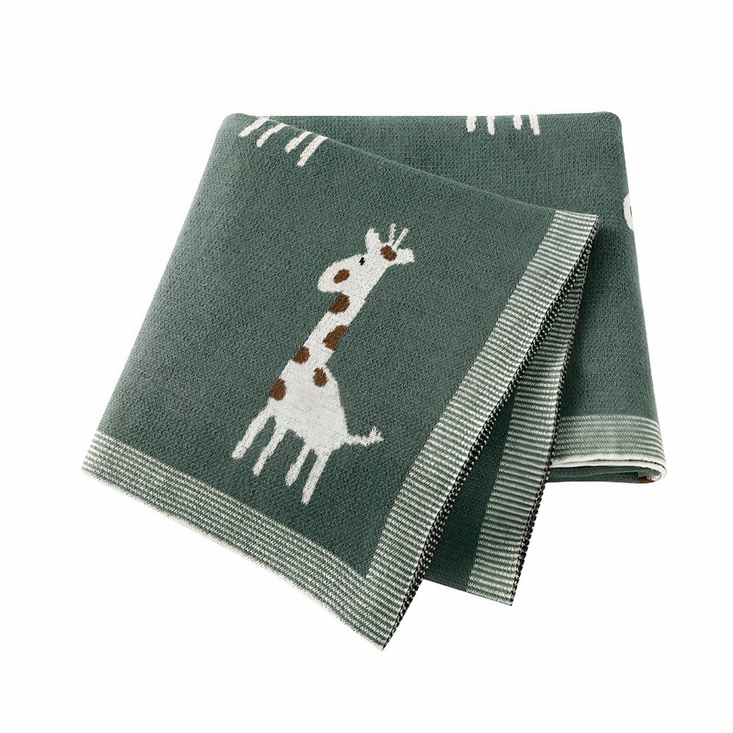 On voit une couverture pliée en quatre sur fond blanc. elle est gris-vert et ornée de petites girafes grises et marron.
