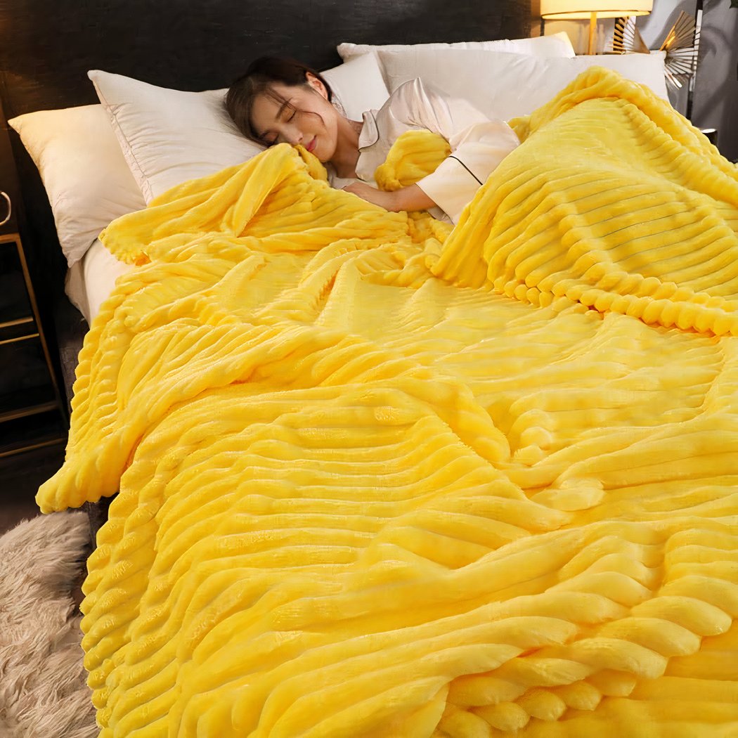 Femme dormant dans un lit recouvert d'une couverture jaune à rayures.
