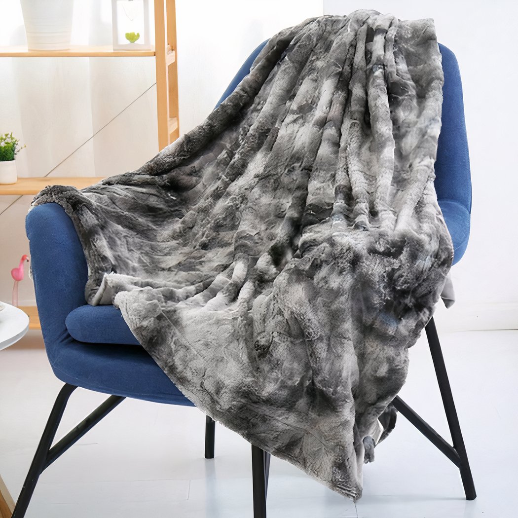 Photo d'une couverture en fausse fourrure grise posé sur une chaise bleue.