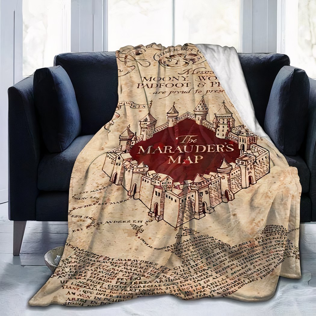 Photo d'une couverture polaire imprimée de la carte du maraudeur de Harry Potter, posée sur un canapé noir devant une fenetre.