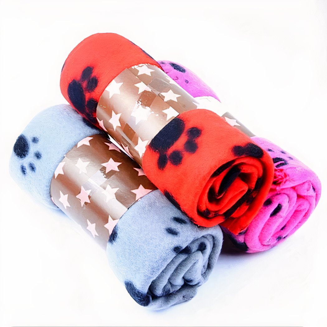 Photo de trois couvertures polaire enroulées et empilées, imprimées de trace de pattes d'animaux.