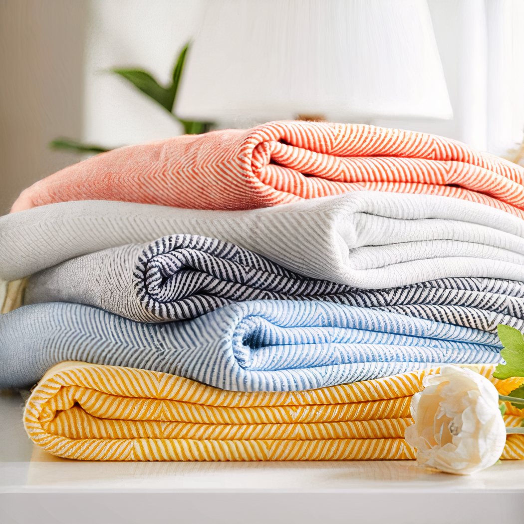 Photo de couvertures tricotés à chevrons coloré empilées.