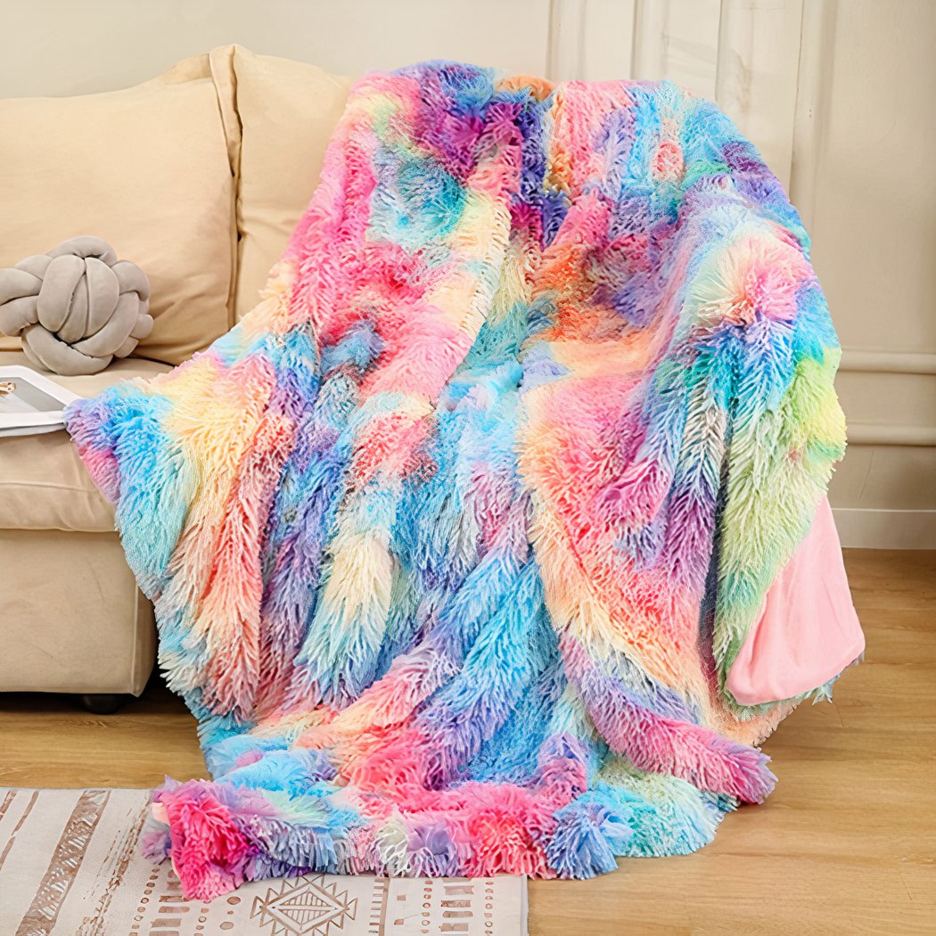 Photo d'une couverture en fausse fourrure multicolore posé sur un coin de canapé beige