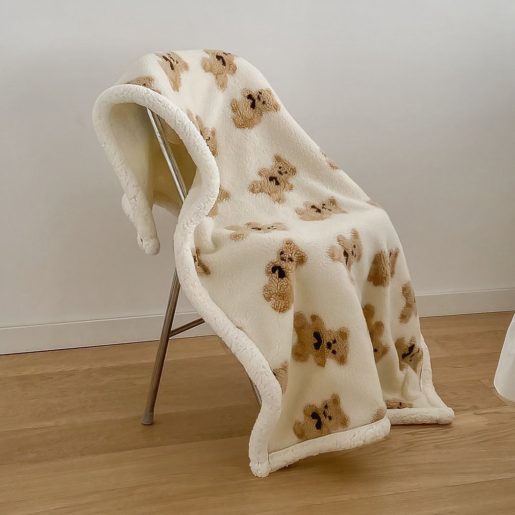 Couverture beige avec des oursons posée sur une chaise