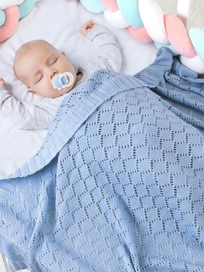 Bébé faisant la sieste dans un lit avec une couverture tricotée en crochet de couleur bleue