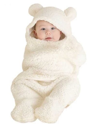 Bébé assis avec une couverture blanche autour de lui avec des oreilles d'ours sur la capuche.