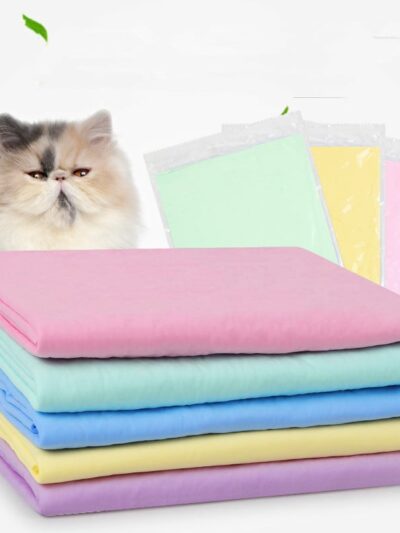 On voit un tas de couvertures colorées devant un chat persan tricolore.