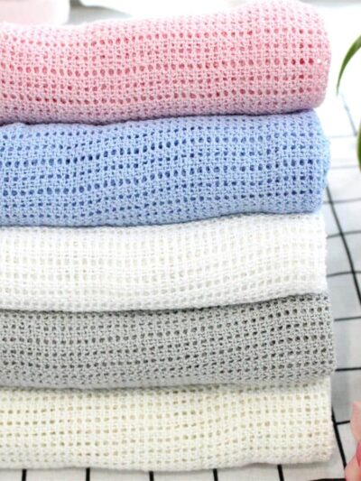 Couverture tricotée en crochet rose, bleu, blanc, gris.