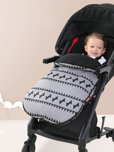 Photo d'un bébé dans une poussette avec une couverture grise imprimé graphique