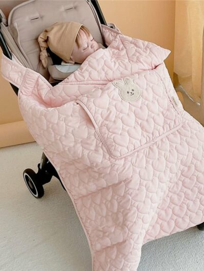 Photo d'un bébé dans une poussette avec une couverture matelassé rose