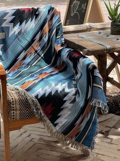 Photo d'une couverture mexicaine style ethnique bohème bleue posée sur une chaise à côté d'une table en bois