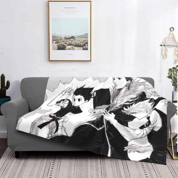 Couverture avec des motifs de hunter x hunter en noir et blanc sur un canapé gris