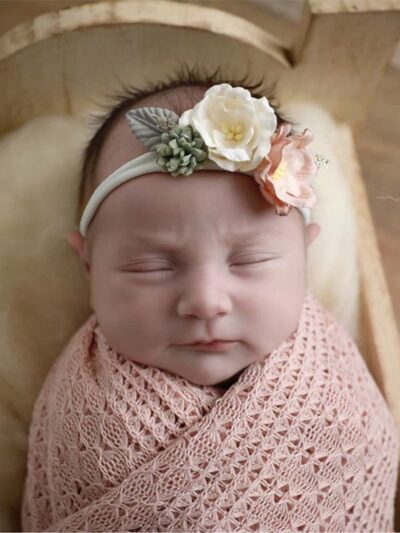 Bébé enveloppé et photographié dans une couverture tricoté en crochet de couleur rose.