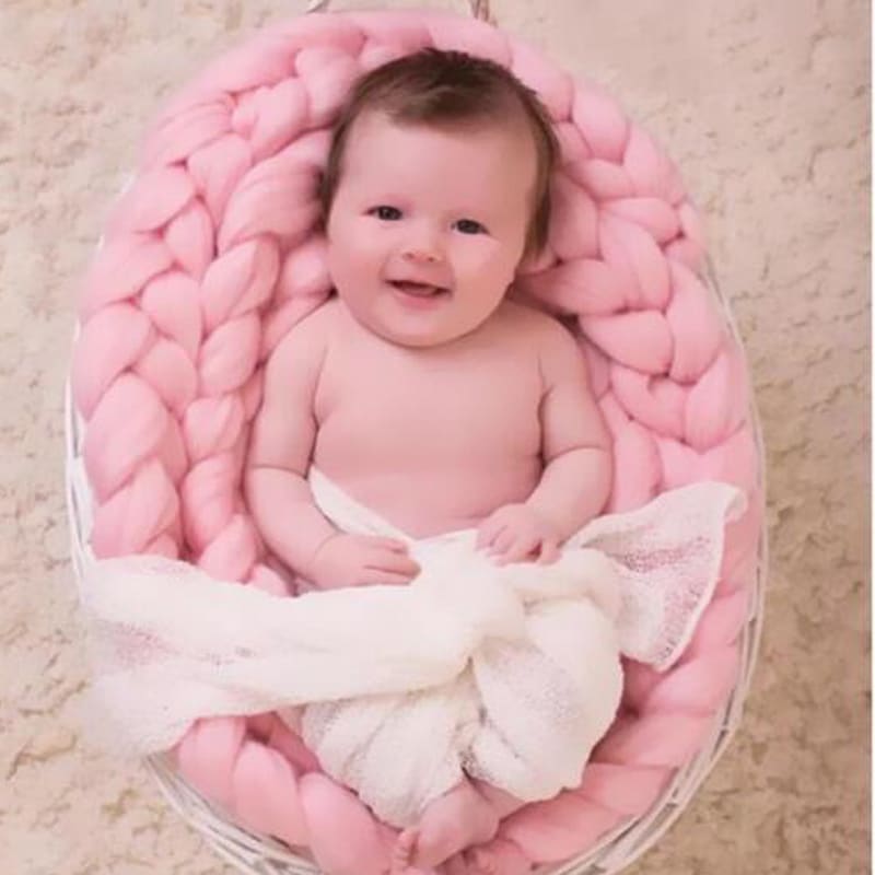 Bébé dans une ouverture pour photographie tricotée en crochet de couleur rose.