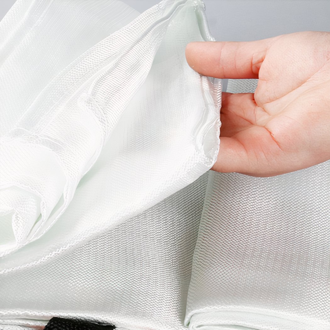 On voit une main qui soulève une couverture anti-feu blanche en fibre de verre.