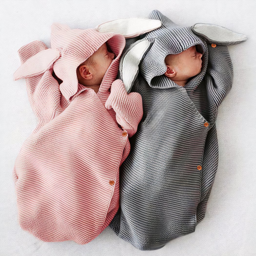 Nouveaux-nés emmaillotés dans une couverture tricotée en crochet de couleur grise et rose.