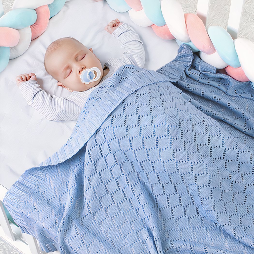 Bébé faisant la sieste dans un lit avec une couverture tricotée en crochet de couleur bleue