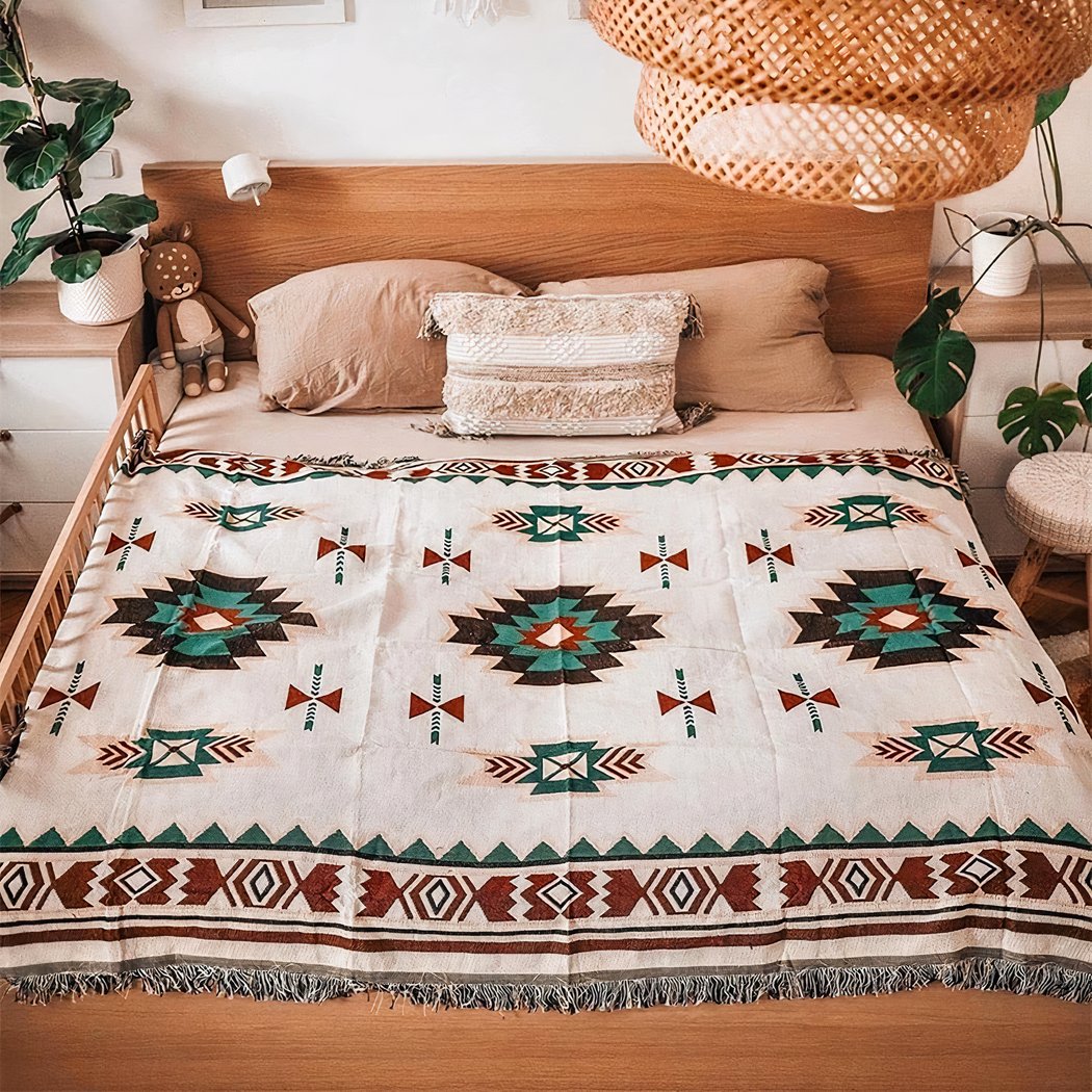 Photo d'une couverture mexicaine à motifs ethnique posée sur un lit en bois