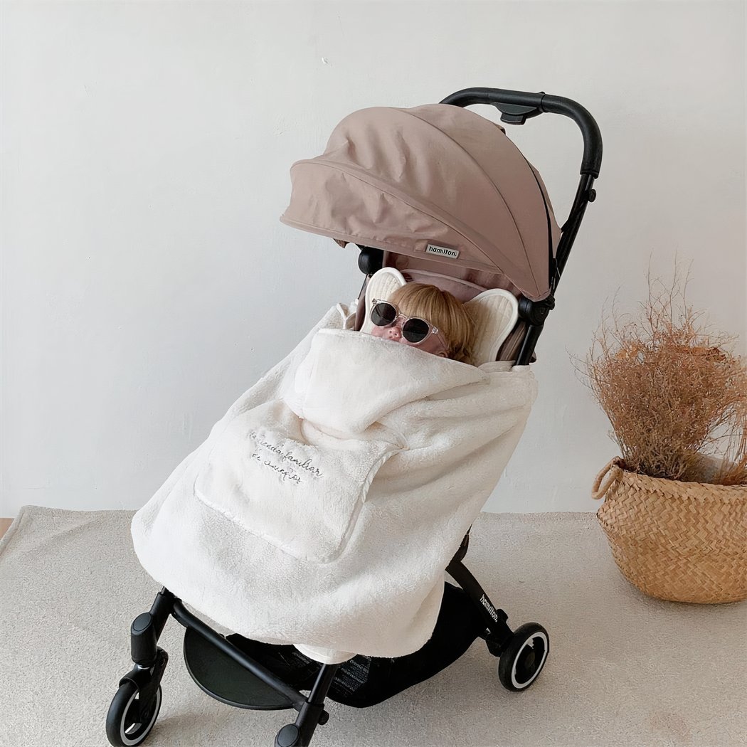 Photo d'un bébé dans une poussette avec une couverture polaire beige