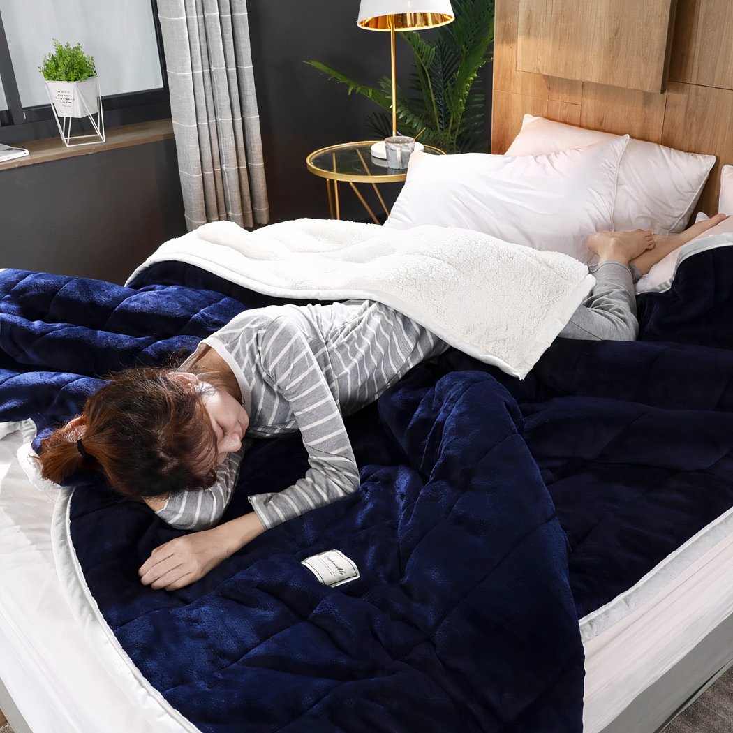 Couverture pondérée de lit pour hiver en polaire bleu avec une femme allongée dessus.