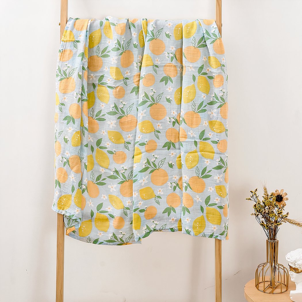 Sur un support en bois, on voit une couverture légère, bleue, avec un imprimé citron et orange.