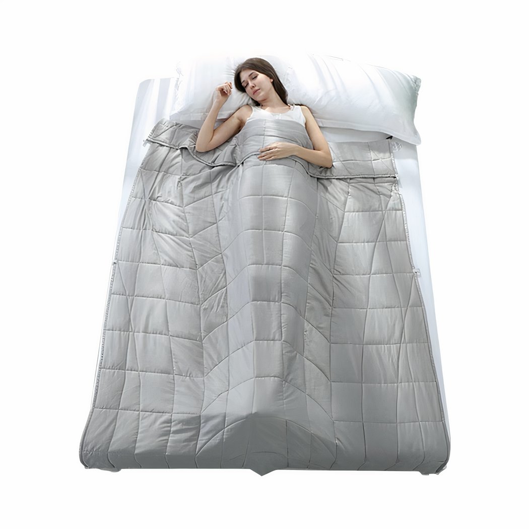 Femme dans un lit avec une couverture pondérée en coton grise