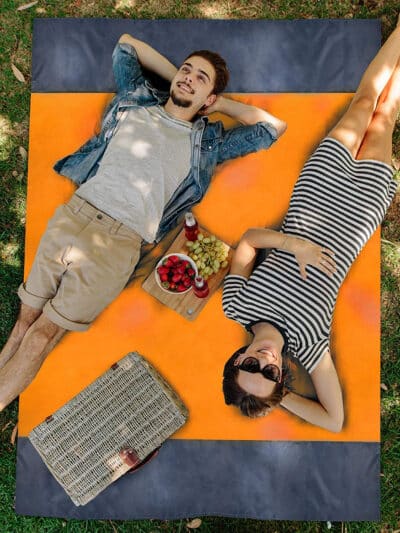 Couverture pique-nique de couleur orange étendue sur l'herbe avec deux personnes allongées dessus