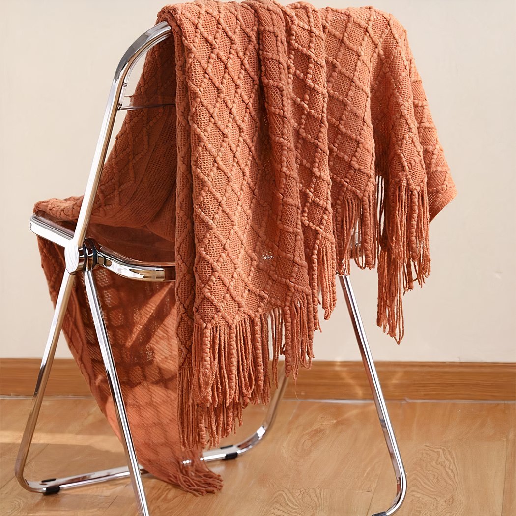 Couverture Pique-nique de couleur marron posée sur une chaise devant un mur blanc et un sol en parquet