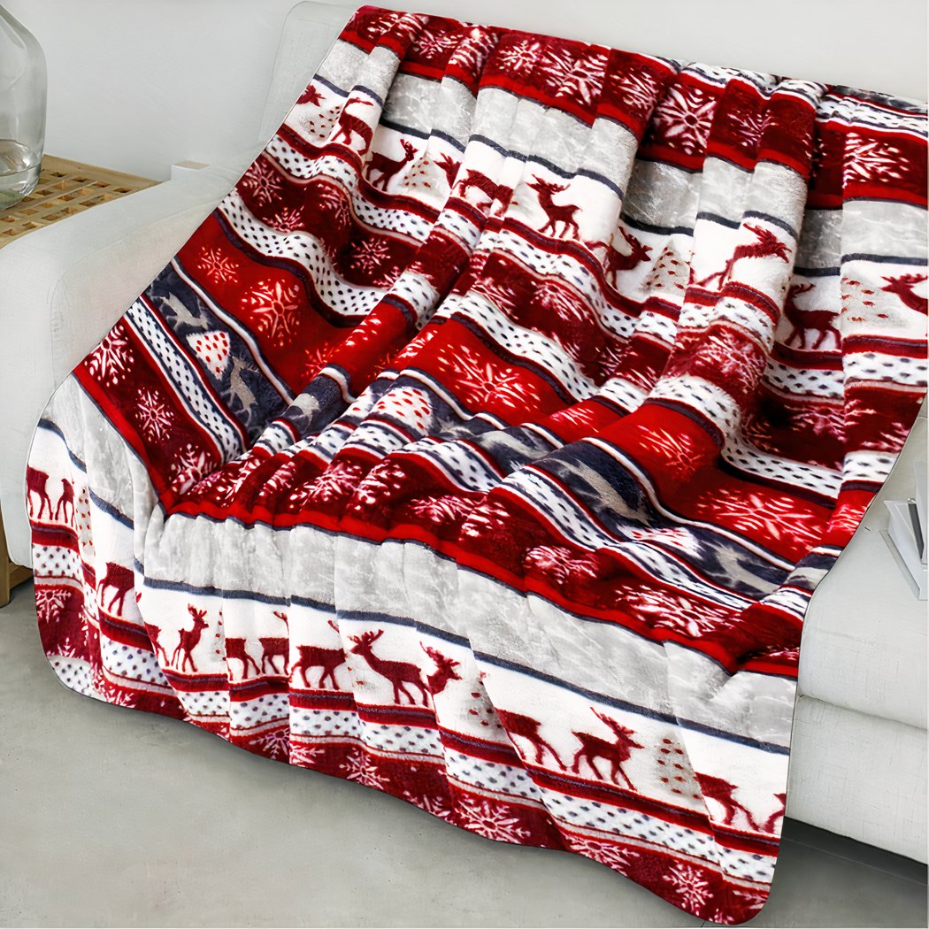 Plaid effet rayé aux couleurs de Noël, rouges, bleu, blanc, beiges. Jeter sur un canapé gris très clair que l'on ne voit presque pas.