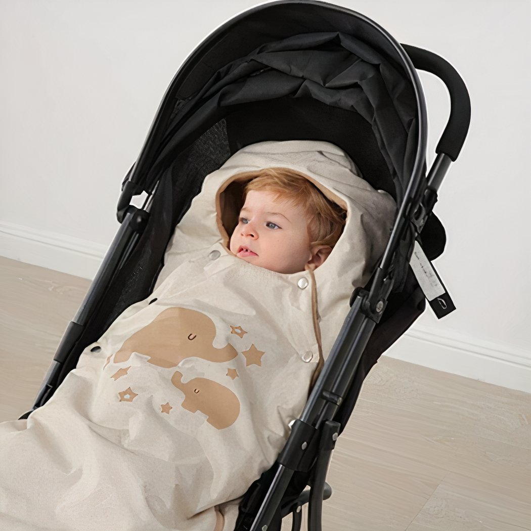 Couverture Poussette Beige et Mignonne pour Bébé sur une poussette noire avec un bébé sur fond beige