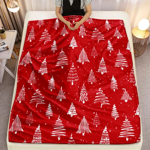 Couverture de Noël en Tissu Microfibre avec Motifs de Sapins posée sur un lit avec une personne dedans