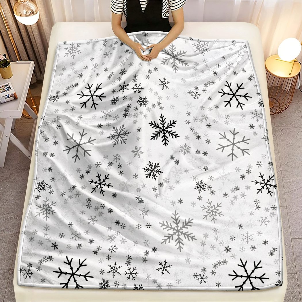 Plaid de Noël en Tissu Microfibre avec Motifs de Flocons de Neige sur un lit avec une personne