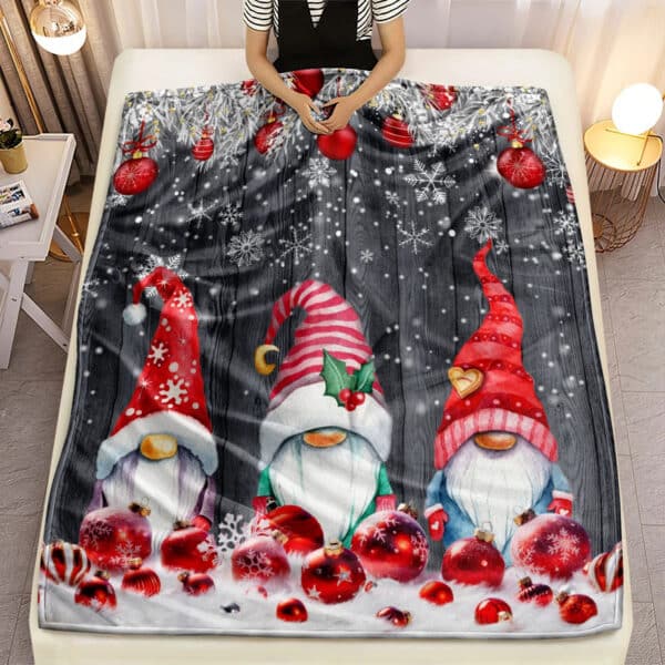 Plaid de Noël en Tissu Microfibre avec Imprimé de Trois Pères Noël sur un lit avec une personne dans le lit