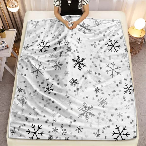 Plaid de Noël en Tissu Microfibre avec Motifs de Flocons de Neige sur un lit avec une personne